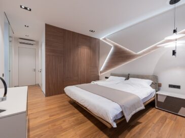 Light modern hotel room interior with soft white bed and wooden floor near cupboard