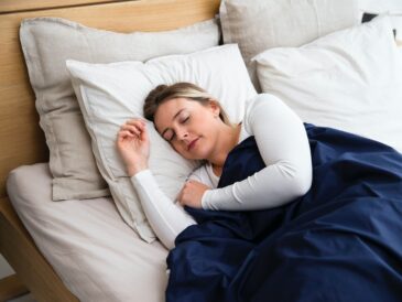 a woman sleeping on a bed with a blue blanket