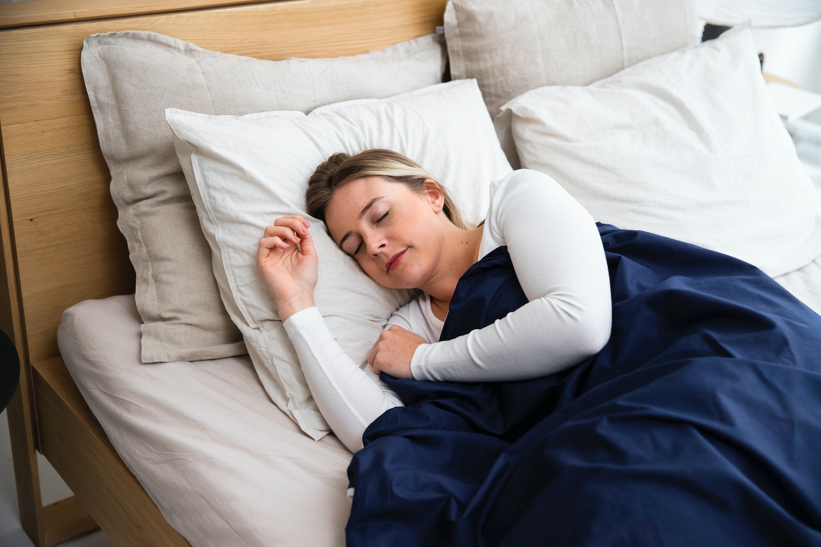 a woman sleeping on a bed with a blue blanket