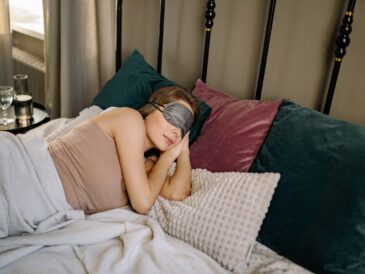 Woman in Brown Tank Top Lying on Bed Wearing Gray Sleeping Mask