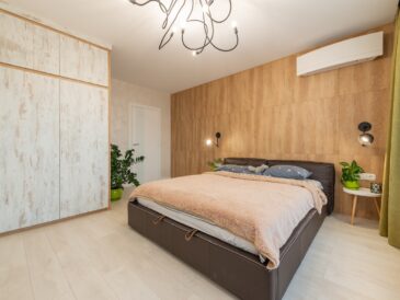Large comfortable bed placed against wooden wall in spacious modern apartment in daytime