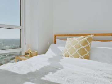 a bed with a white comforter and a yellow pillow