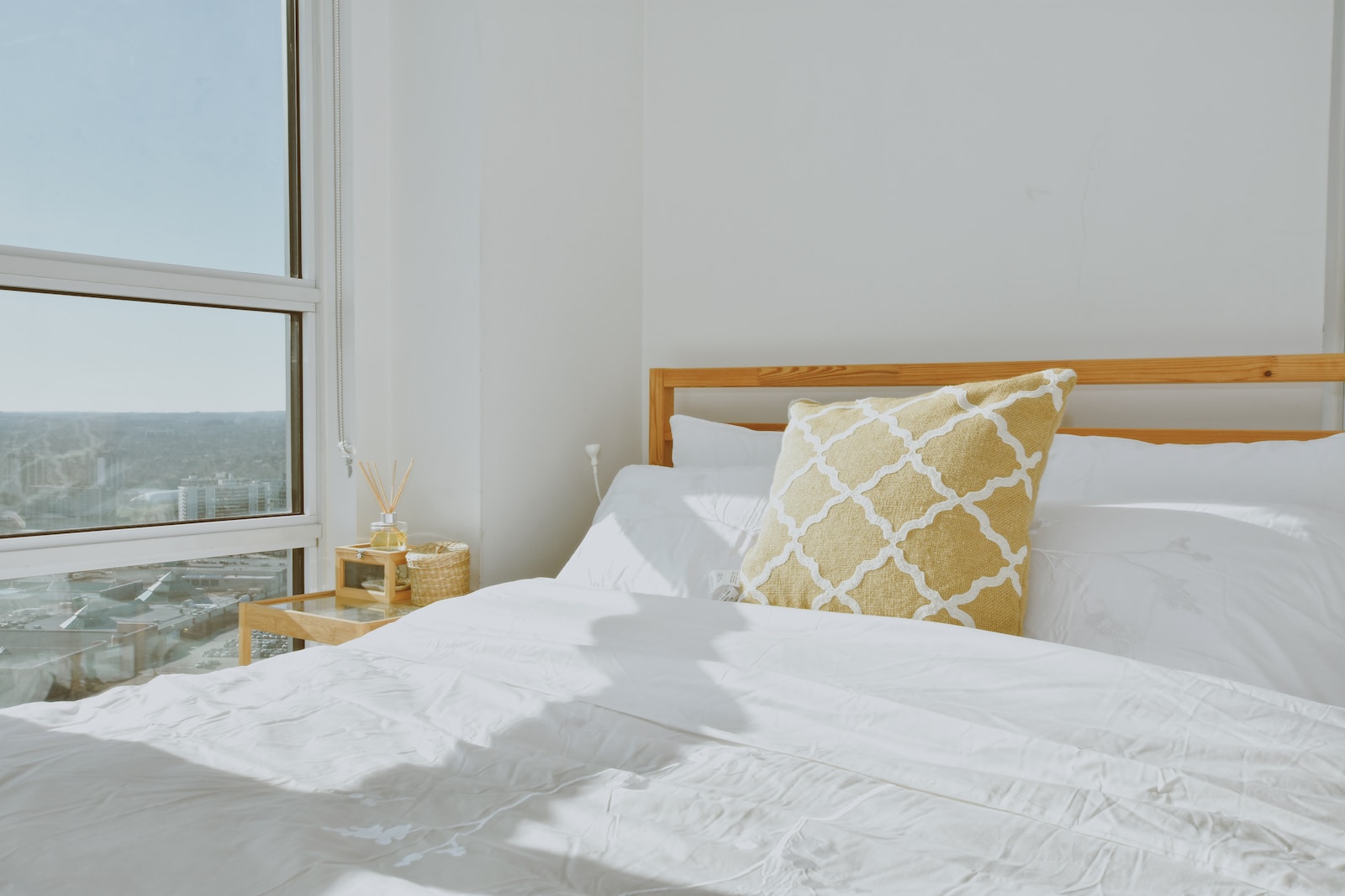 a bed with a white comforter and a yellow pillow