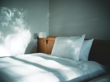 white bed linen beside brown wooden nightstand