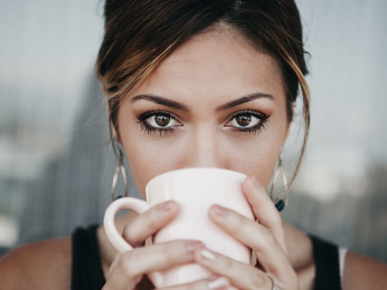 woman drinking from white coffee cup